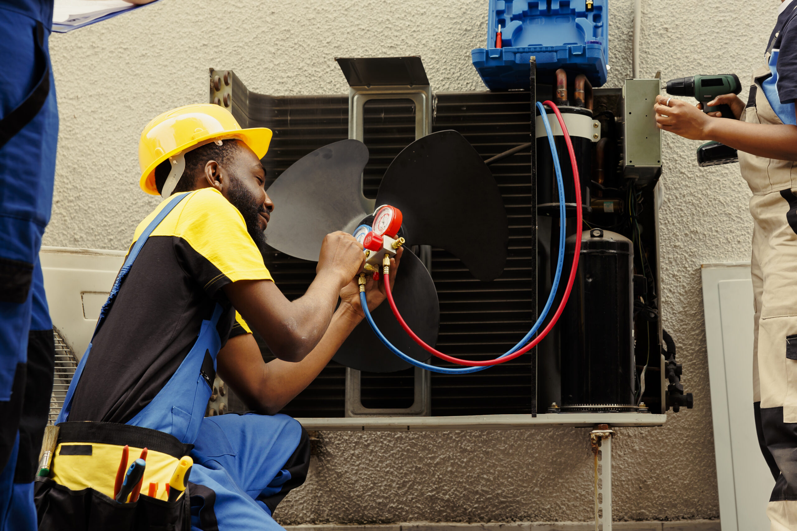 HVAC technicians servicing an outdoor unit with tools and safety gear.