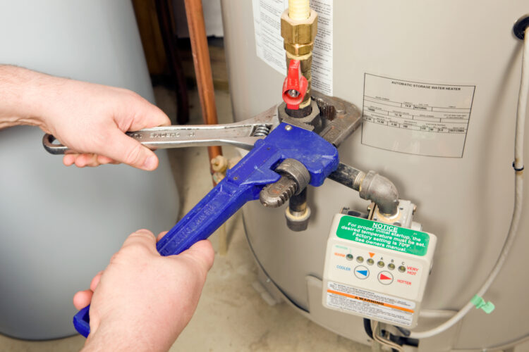 Technician performing water heater repairs with wrenches