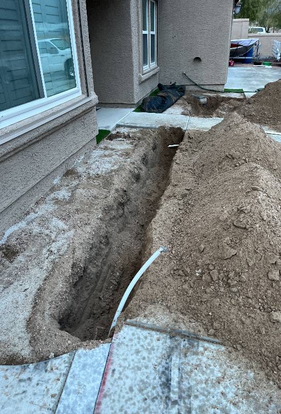 Residential sewer line repair in progress with dug-out trench